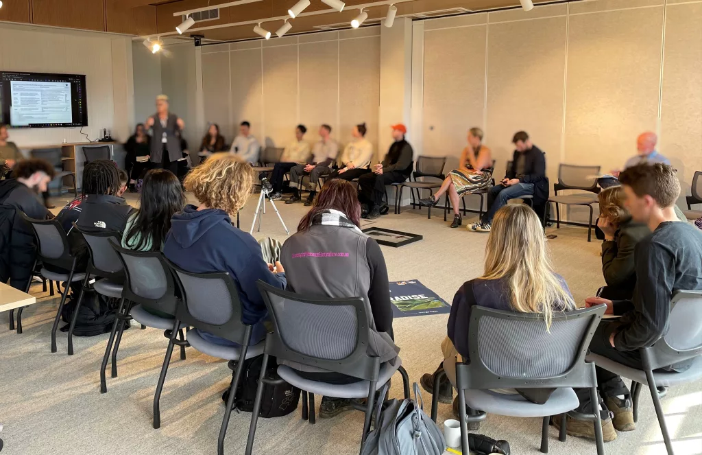 People of all ages and genders gathered around a oval meeting table in a community meeting room.